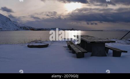 Area pic-nic con tavolo in legno e panchine al parcheggio lungo la strada E69 con vista sul porto di Honningsvåg, Norvegia, Scandinavia in inverno. Foto Stock