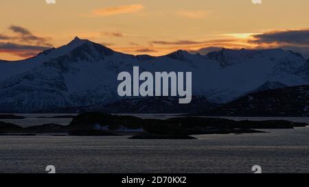 Vista mozzafiato sulle montagne rocciose innevate, sulla riva di un fiordo vicino a Brensholmen, Norvegia, Scandinavia, con un cielo bellissimo e colorato durante il tramonto. Foto Stock