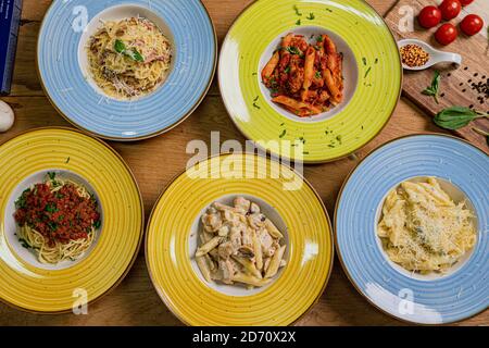 Diversi piatti di pasta e spaghetii con diversi tipi di salsa su sfondo di legno, vista dall'alto. Concetti di cibo italiano. Foto Stock