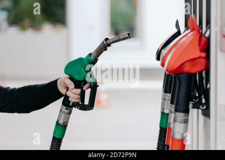 Concetto di rifornimento auto. Mani con l'ugello del carburante presso la stazione di servizio. Primo piano delle pistole di rifornimento. Diesel e gas. Servizio moderno Foto Stock