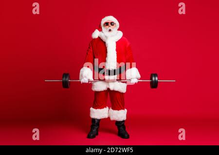 Foto a lunghezza intera della barba bianca del vecchio uomo in pensione l'addestramento del barbell ha scioccato troppo pesante indossa il cappotto del costume di santa x-mas stivali in pelle per copricapo da sole Foto Stock