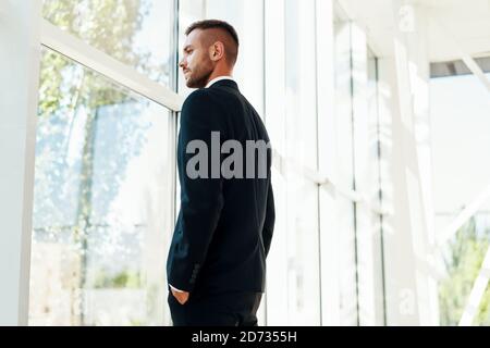 Profilo di uomo d'affari sicuro in elegante suite in moderno ufficio creativo con finestre panoramiche Foto Stock