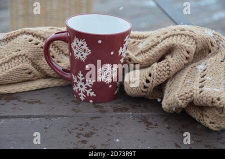 Coppa rossa o borgogna con un modello di fiocchi di neve sullo sfondo di una foresta invernale. Nevicare. Capodanno. Natale. Tazza con una bevanda calda al vento Foto Stock