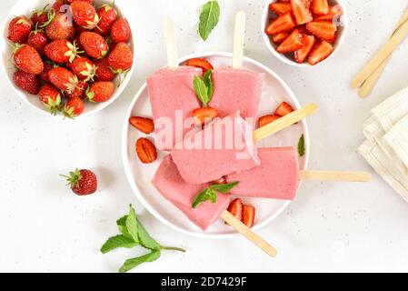 Popsicle di gelato alla fragola su piatto bianco. Gustoso dessert estivo. Vista dall'alto, disposizione piatta Foto Stock