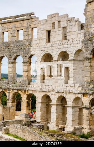 Dettagli di archi e colonne nelle pareti esterne dell'iconico antico anfiteatro romano di Pola, Istria, Croazia, una delle principali attrazioni turistiche Foto Stock