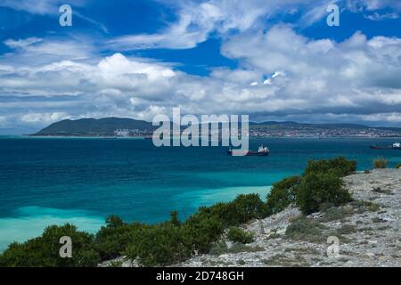 Mare blu con navi da carico contro il cielo blu nuvoloso Foto Stock