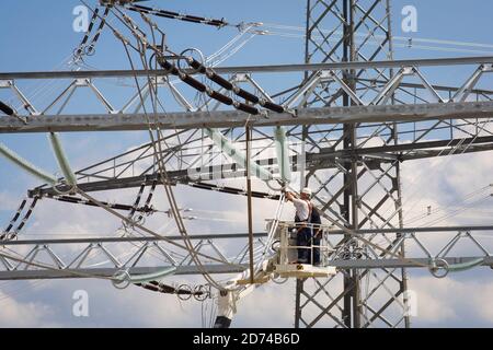 I lavoratori collegano le linee ad alta tensione alla centrale elettrica alimentata a lignite Neurath, vicino a Grevenbroich, Renania settentrionale-Vestfalia, Germania. July2009 arbeiter brin Foto Stock