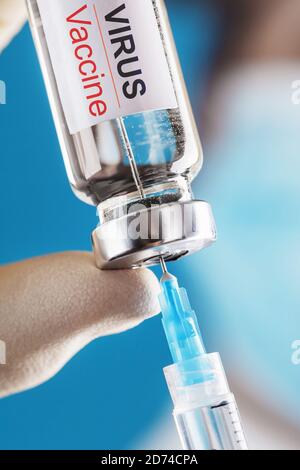 Ampolla con il vaccino contro il virus da malattie su sfondo blu nelle mani di un medico, scienziato in guanti e una maschera. Spazio libero su Foto Stock