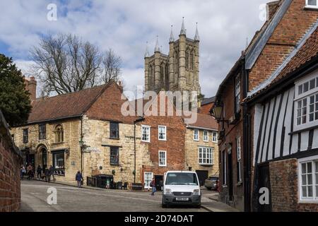 Persone che camminano su ripida Hill, un'antica strada medievale a Lincoln, Regno Unito Foto Stock