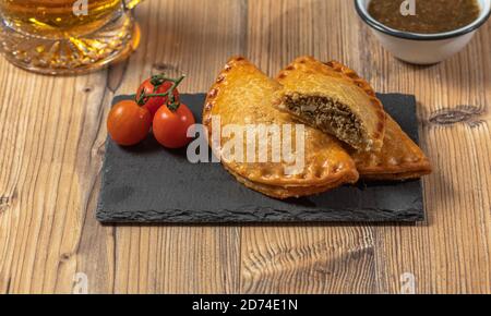 Empanadas argentini con un bicchiere di birra su un legno tabella Foto Stock