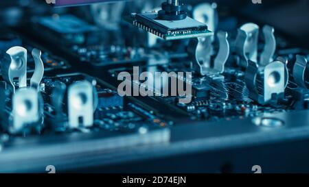 Close-up Macro Shot della scheda elettronica a circuito stampato in fase di assemblaggio con braccio robotizzato automatizzato, tecnologia a montaggio superficiale che collega i microchip Foto Stock