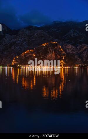 Vista notturna della Baia di Kotor con un'antica fortezza illuminata mura della città in montagna, Kotor, Montenegro, sul mare Adriatico Foto Stock