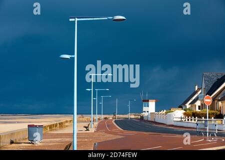 Strandpromenade in der Normandie. Dramatischer, veloce schwarzer Himmel kurz bevor der Regen einsetzt. Sehr grafisches Bild mit tollen Laternen Foto Stock