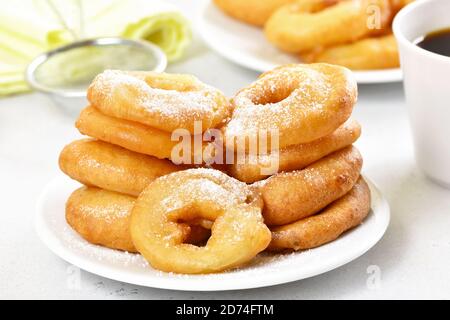 Ciambelle fatte in casa con zucchero in polvere su piatto bianco, vista ravvicinata Foto Stock