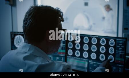 Nel laboratorio medico il paziente viene sottoposto a un processo di scansione RM o TC sotto la supervisione di un radiologo, nella procedura di monitoraggio medico della sala di controllo e dei monitor Foto Stock