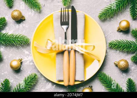 Vista superiore del nuovo anno la cena festiva su sfondo di cemento. Composizione della piastra forcella, coltello, abete e decorazioni. Buon Natale concetto. Foto Stock