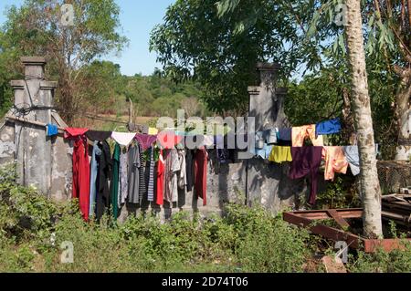 Vista di molti abiti colorati appesi su una linea di lavaggio Nel villaggio di Otres Beach in Cambogia su un giorno di sole Foto Stock