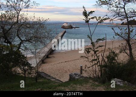 Scuola di vela Cantabria Santander Spagna sull'Isla de la Torre nella baia vista dalla spiaggia con un molo che si estende verso l'isola Foto Stock