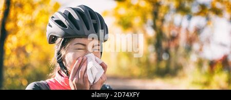 Tosse nel tessuto che copre il naso e la bocca quando tosse all'esterno come COVID-19 linee guida igieniche per la prevenzione della diffusione di Coronavirus. Bicicletta ciclista ragazza Foto Stock