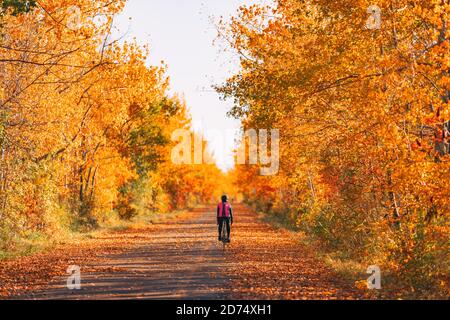 Bicicletta ciclista in bicicletta nella foresta autunnale con splendidi paesaggi di foglie rosse di autunno fogliame. Pedalando su strada Foto Stock