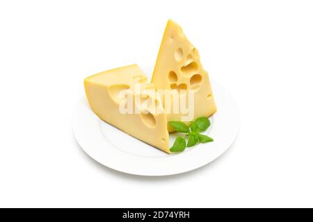 Due pezzi di formaggio a forma di cuneo con grandi fori e fresco basilico su una piastra bianca isolata su sfondo bianco Foto Stock