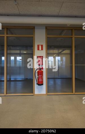 Vista su due uffici vuoti con pareti in vetro. Estintore rosso sulla parete bianca tra gli uffici. Foto Stock