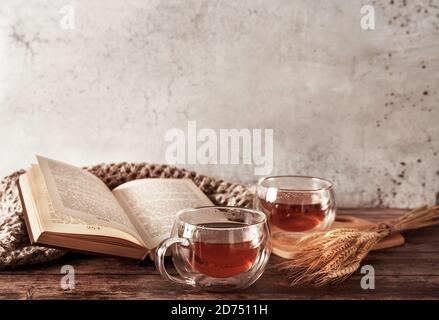Bella sagoma rustica di due tazze di tè e libro su sfondo di legno. Accogliente sfondo autunno naturale. Concetto autunnale. Stile di posa piatto. Carta d'epoca con sfondo autunnale per il design concettuale. Foto Stock