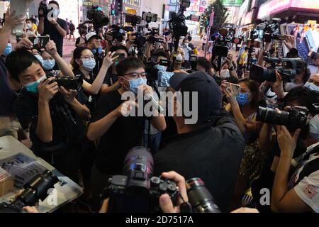 L'attivista pro-democrazia Joshua Wong indossando una maschera mentre si confrontava con un manifestante pro-Pechino durante la manifestazione.gli attivisti pro-democrazia di Hong Kong hanno avviato una campagna sui social media a sostegno dei dodici giovani manifestanti presumibilmente incarcerati sulla terraferma dopo un fallito tentativo di fuggire a Taiwan con un motoscafo. I sostenitori sono incoraggiati a scattare foto del mare attraverso un segno trasparente e a caricarle sui social media con l'hashtag ''SAVE12'. Foto Stock