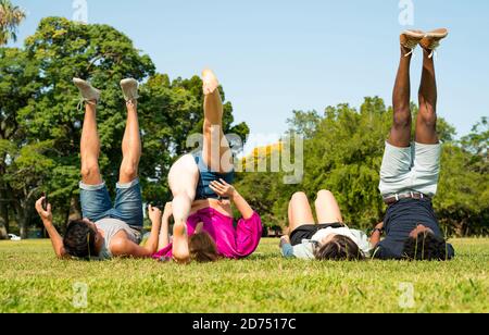 Un gruppo di amici che si adagiano insieme nel prato in un parco in una soleggiata giornata estiva. Foto Stock