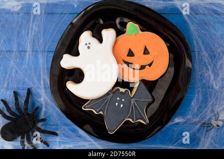 Vista dall'alto dei biscotti di Halloween su un tavolo di legno blu decorato con ragnatela e ragni Foto Stock