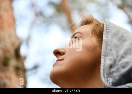 Turista con uno zaino e un cappuccio a pineta sempreverde. Viaggi, ecoturismo, ecologia, concetto di turismo locale, sfondo naturale, esploratore, felpa con cappuccio Foto Stock