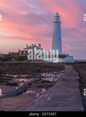 Un glorioso tramonto che illumina le nuvole sul faro di St Mary a Whitley Bay, sulla costa del Northumberland, Inghilterra, Regno Unito Foto Stock