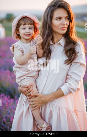 Madre abbraccia figlia al tramonto nel campo di lavanda. Foto Stock