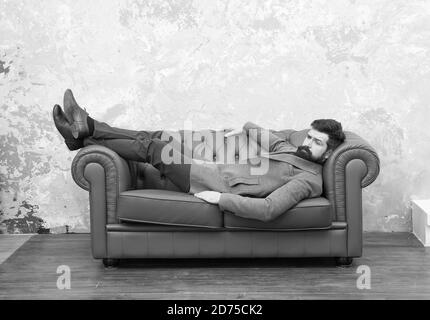 Aspetto bello e soggiorno di moda. Brutale hipster rilassarsi sul divano. Uomo bearded con look di moda. Moda e stile uomo. Abbigliamento casual per affari. Negozio di abbigliamento da uomo. Moda unica come voi. Foto Stock