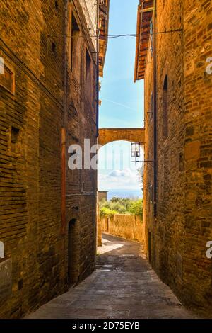 Scorrete un vicolo stretto nel centro storico della città medievale di San Gimignano, Patrimonio dell'Umanità dell'UNESCO, Siena, Toscana, Italia Foto Stock