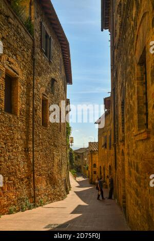 Scorrete un vicolo stretto nel centro storico della città medievale di San Gimignano, Patrimonio dell'Umanità dell'UNESCO, Siena, Toscana, Italia Foto Stock