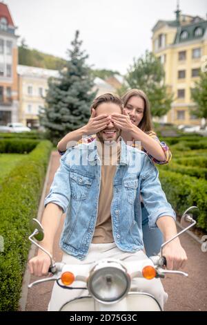 Donna che si diverte con l'uomo che guida uno scooter
