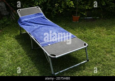 Letto pieghevole aperto con un asciugamano in un giardino Foto Stock