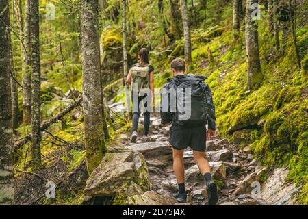 Escursione coppia escursionisti sentiero forestale in autunno natura andare campeggio con zaini. Amici donna e uomo che camminano in salita sulla montagna in Quebec Foto Stock