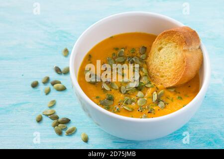 Zuppa di zucca con semi di zucca e timo su un blu sfondo Foto Stock