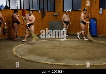 I lottatori sumo puliscono il pavimento di sabbia dell'anello di wrestling Durante la pausa di allenamento mattutino.Koto City.Tokyo.Japan Foto Stock