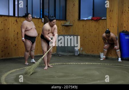 I lottatori sumo puliscono il pavimento di sabbia dell'anello di wrestling Durante la pausa di allenamento mattutino.Koto City.Tokyo.Japan Foto Stock