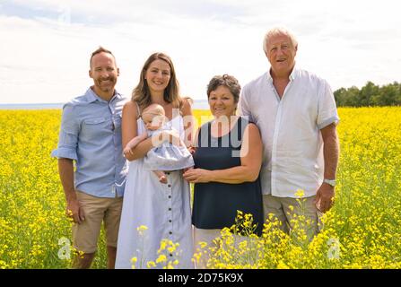 Nonni felici con la nipote del bambino godendo momento in bello campo giallo con il padre Foto Stock