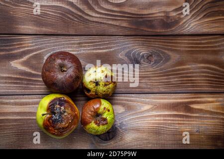 Mele marcio e ammuffite su sfondo di legno. Layout piatto. Spazio di copia Foto Stock