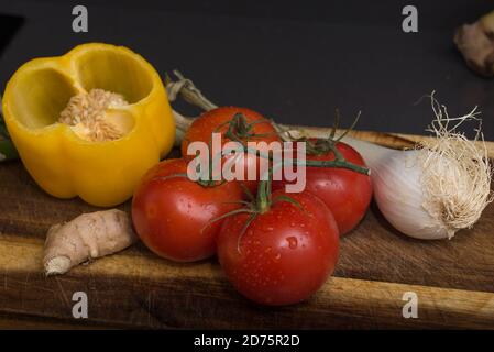 INGREDIENTI PER CUCINARE SU UNA BASE DI LEGNO PEPERONI AGLIO ONION POMODORO E AGLIO Foto Stock