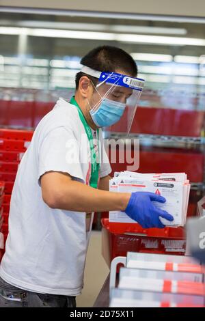 Renton, Washington, Stati Uniti. 20 Ottobre 2020. Un addetto alle elezioni carica i voti in una macchina di smistamento presso il quartier generale delle elezioni della King County. Credit: Paul Christian Gordon/Alamy Live News Foto Stock