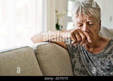 Ritratto di piangere donna anziano su divano che soffre di depressione Foto Stock
