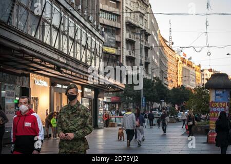 BELGRADO, SERBIA - 10 OTTOBRE 2020: Due uomini, tra cui un soldato dell'esercito serbo in uniforme camminando per le strade di belgrado con volto mas Foto Stock