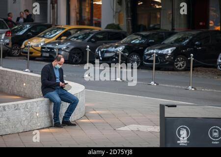 BELGRADO, SERBIA - 10 OTTOBRE 2020: Uomo che indossa una maschera respiratoria che controlla le app sul suo smartphone nella strada di Belgrado, durante il coronav Foto Stock