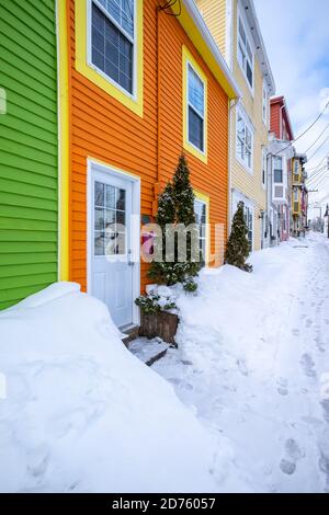 Molteplici pareti esterne o edifici dai colori vivaci. Ci sono cumuli di neve accatastati sul marciapiede di fronte agli edifici. Foto Stock